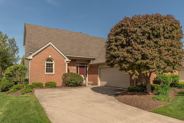 4980 Doral Dr, Ann Arbor, MI 48108 - view of front of property featuring brick siding, driveway, an attached garage, and roof with shingles