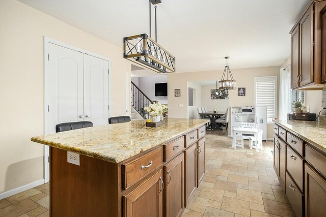 9908 Mariner St, Portage, MI 49002 - kitchen featuring stone tile flooring, a chandelier, light stone countertops, hanging light fixtures, and a center island