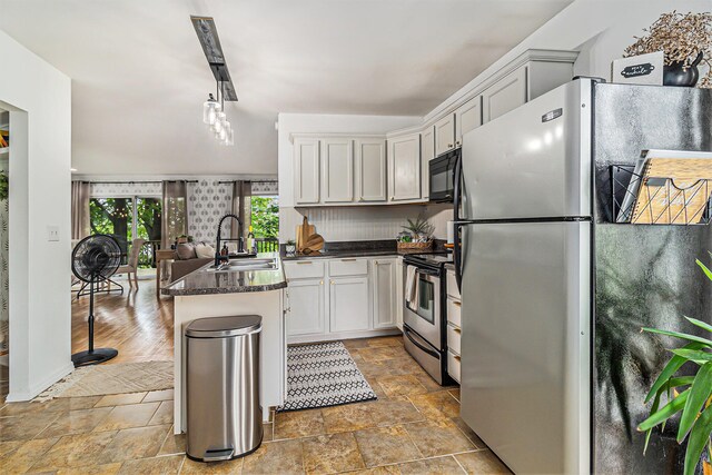 524 S Mears Ave, Whitehall, MI 49461 - kitchen featuring a sink, stainless steel appliances, dark countertops, light stone finish flooring, and a peninsula