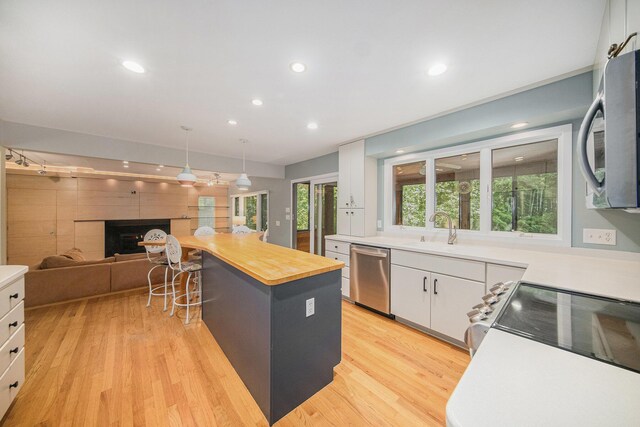 1410 N Folkstone Ct, Ann Arbor, MI 48105 - kitchen featuring appliances with stainless steel finishes, light wood-style floors, white cabinetry, a fireplace, and recessed lighting
