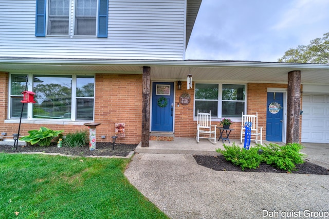 view of exterior entry featuring a porch, brick siding, and a garage