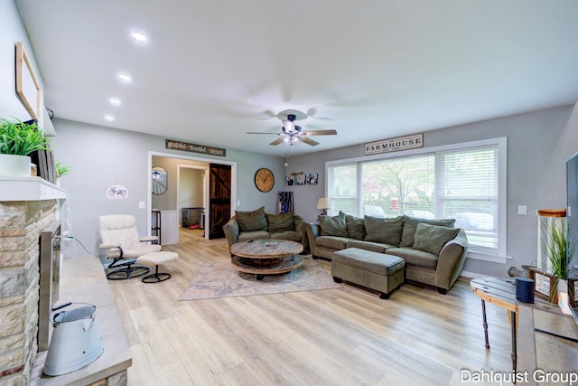 living room featuring a fireplace, ceiling fan, light wood-type flooring, and recessed lighting