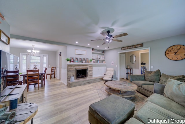 living room featuring a chandelier, a ceiling fan, light wood-type flooring, a stone fireplace, and recessed lighting