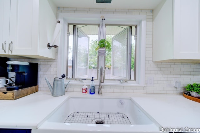 kitchen featuring white cabinets, tasteful backsplash, light countertops, and a sink