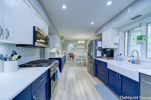 kitchen featuring appliances with stainless steel finishes, blue cabinetry, white cabinets, tasteful backsplash, and recessed lighting