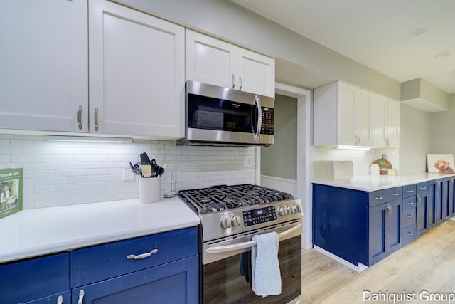 kitchen featuring appliances with stainless steel finishes, blue cabinetry, tasteful backsplash, and light countertops