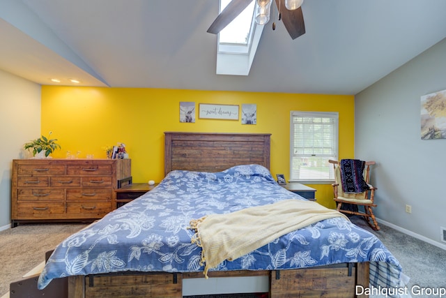 bedroom featuring carpet floors, vaulted ceiling, a skylight, baseboards, and a ceiling fan