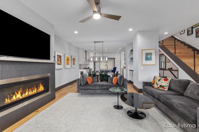 657 Greenslate Dr SE, Ada, MI 49301 - living room featuring light wood-style flooring, stairs, a tile fireplace, baseboards, and ceiling fan