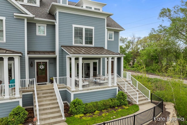 657 Greenslate Dr SE, Ada, MI 49301 - view of front facade featuring a shingled roof, covered porch, a standing seam roof, and stairs