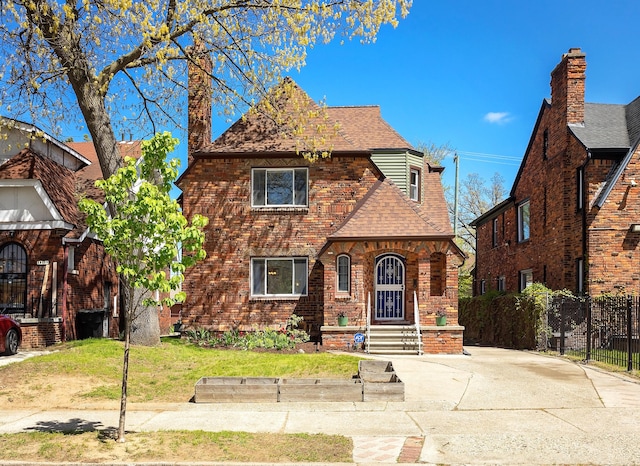 18106 Roselawn St, Detroit, MI 48221 - tudor home with a shingled roof, fence, a chimney, and brick siding