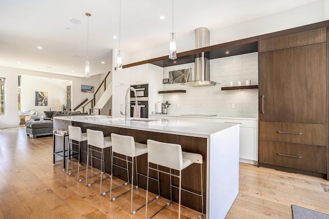 26 W 6th St, Holland, MI 49423 - kitchen featuring wall chimney exhaust hood, modern cabinets, white cabinetry, light wood-style floors, and decorative backsplash