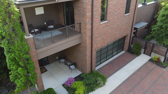 26 W 6th St, Holland, MI 49423 - rear view of house with an attached garage, a balcony, and brick siding