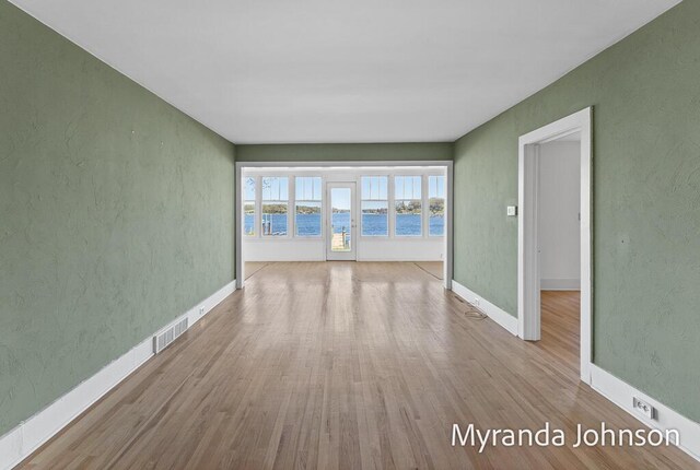 15926 Beach Dr, Spring Lake, MI 49456 - spare room with wood finished floors, a water view, baseboards, and a textured wall
