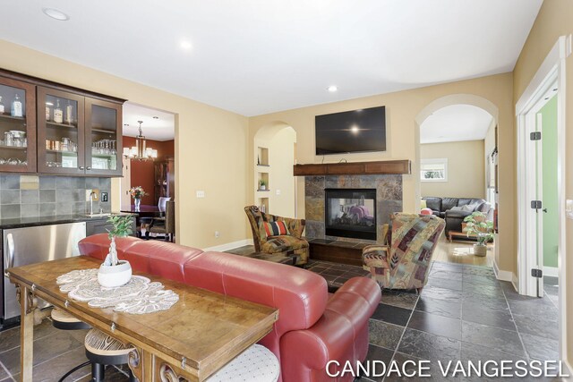 2429 Shears Crossing Ct NE, Grand Rapids, MI 49525 - living room featuring arched walkways, stone tile floors, a tiled fireplace, baseboards, and recessed lighting