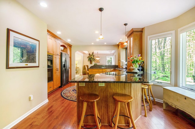 8461 Webster Hills Rd, Dexter, MI 48130 - kitchen featuring black appliances, a peninsula, light wood-style flooring, baseboards, and arched walkways