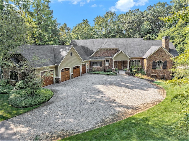 4850 Catamount Trl NE, Ada, MI 49301 - view of front of home with an attached garage, a chimney, driveway, stone siding, and a shingled roof