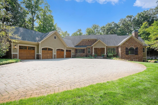 4850 Catamount Trl NE, Ada, MI 49301 - view of front of house featuring stone siding, decorative driveway, a garage, a chimney, and a front yard