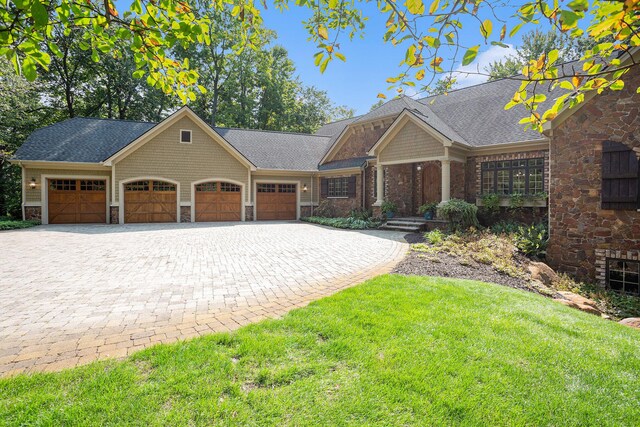 4850 Catamount Trl NE, Ada, MI 49301 - view of front facade featuring a garage, decorative driveway, stone siding, a front lawn, and a shingled roof