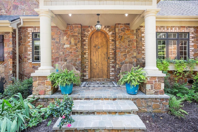 4850 Catamount Trl NE, Ada, MI 49301 - view of exterior entry with covered porch, a shingled roof, and brick siding