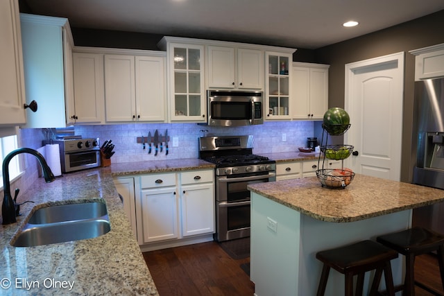 16894 Arbor Way Dr, Nunica, MI 49448 - kitchen with stainless steel appliances, a sink, recessed lighting, white cabinetry, and a breakfast bar