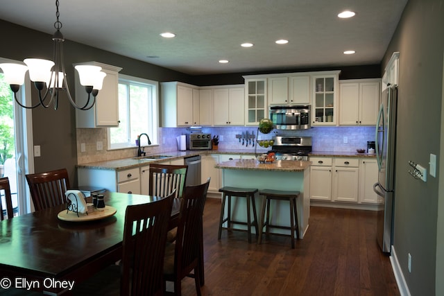 16894 Arbor Way Dr, Nunica, MI 49448 - kitchen with stainless steel appliances, a sink, a kitchen island, white cabinets, and backsplash