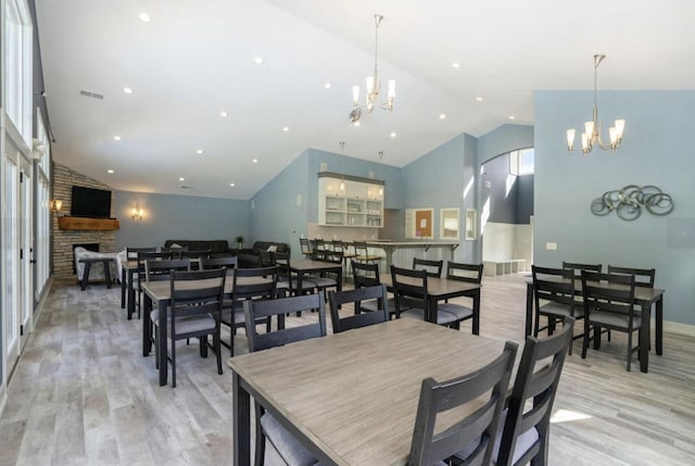 16894 Arbor Way Dr, Nunica, MI 49448 - dining room featuring a chandelier, light wood-type flooring, a stone fireplace, baseboards, and high vaulted ceiling