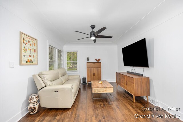 living area with a ceiling fan, dark wood-style flooring, and baseboards