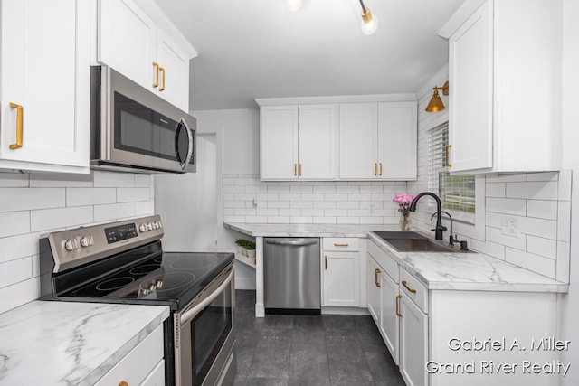 kitchen featuring appliances with stainless steel finishes, a sink, white cabinets, and backsplash