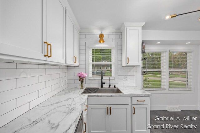 kitchen featuring a sink, white cabinetry, backsplash, and healthy amount of natural light