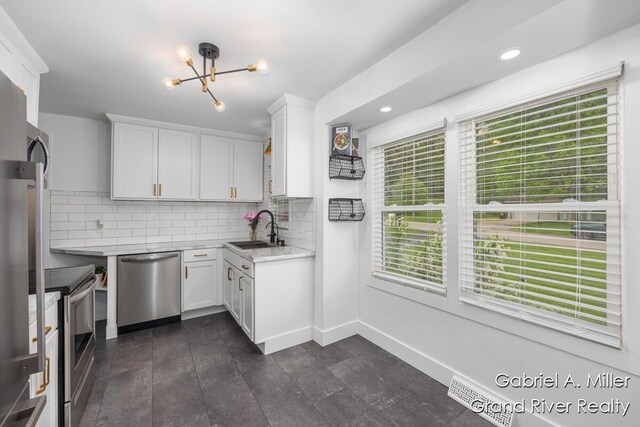 kitchen with appliances with stainless steel finishes, a sink, a chandelier, white cabinetry, and recessed lighting