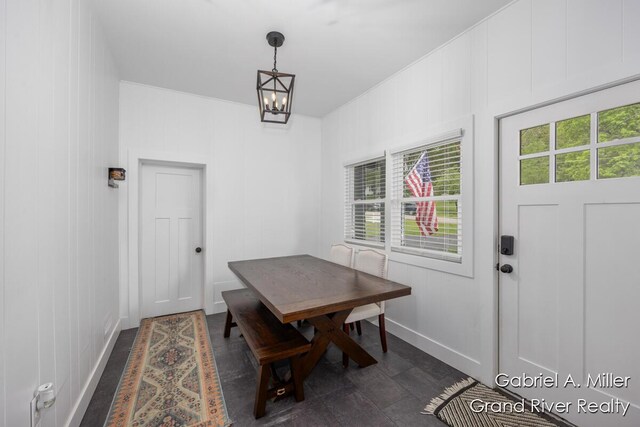 dining room with healthy amount of natural light, a chandelier, baseboards, and a decorative wall