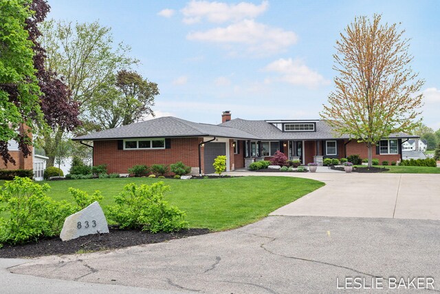 833 Allen Dr, Holland, MI 49423 - view of front of home featuring brick siding, an attached garage, a front lawn, a chimney, and concrete driveway