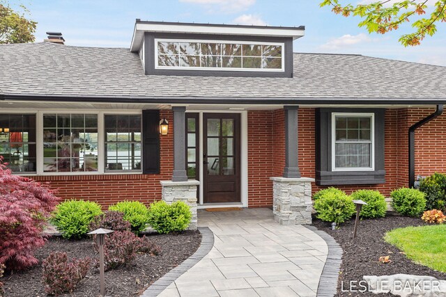 833 Allen Dr, Holland, MI 49423 - doorway to property featuring a porch, a shingled roof, a chimney, and brick siding