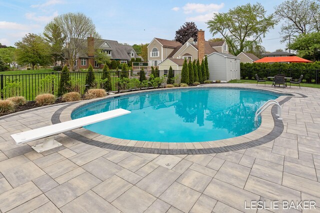 833 Allen Dr, Holland, MI 49423 - view of swimming pool with a storage unit, a diving board, a residential view, an outdoor structure, and a patio area