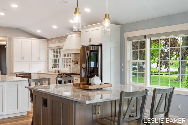 833 Allen Dr, Holland, MI 49423 - kitchen featuring stainless steel refrigerator with ice dispenser, plenty of natural light, a center island, lofted ceiling, and recessed lighting
