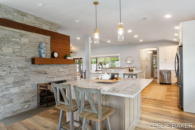 833 Allen Dr, Holland, MI 49423 - kitchen with light wood-type flooring, white cabinetry, a kitchen breakfast bar, light stone counters, and stainless steel appliances