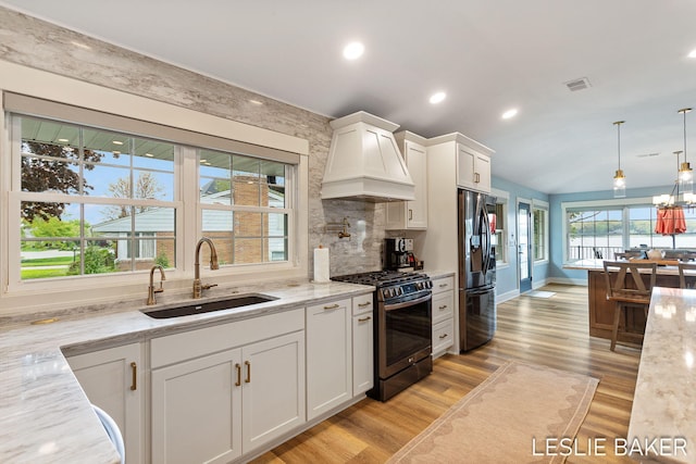 833 Allen Dr, Holland, MI 49423 - kitchen featuring appliances with stainless steel finishes, a sink, custom exhaust hood, white cabinets, and light stone counters