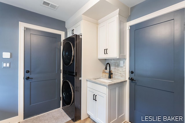 833 Allen Dr, Holland, MI 49423 - clothes washing area featuring stacked washer / dryer and cabinet space