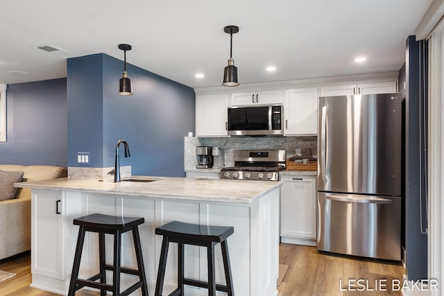 833 Allen Dr, Holland, MI 49423 - kitchen with stainless steel appliances, a sink, white cabinets, light wood-style floors, and recessed lighting