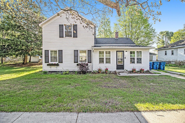 620 N Lakeshore Dr, Ludington, MI 49431 - traditional-style house featuring a chimney, a front lawn, and entry steps