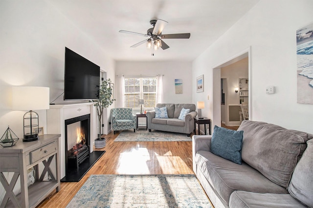 620 N Lakeshore Dr, Ludington, MI 49431 - living area with a warm lit fireplace, a ceiling fan, and light wood-style flooring