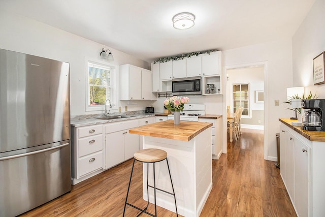 620 N Lakeshore Dr, Ludington, MI 49431 - kitchen featuring appliances with stainless steel finishes, a sink, butcher block countertops, and white cabinetry