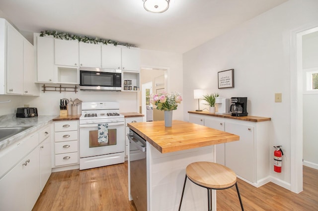 620 N Lakeshore Dr, Ludington, MI 49431 - kitchen with appliances with stainless steel finishes, butcher block counters, open shelves, light wood-style floors, and a kitchen breakfast bar