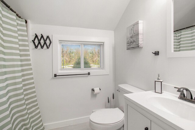 620 N Lakeshore Dr, Ludington, MI 49431 - full bathroom with toilet, vanity, vaulted ceiling, and baseboards
