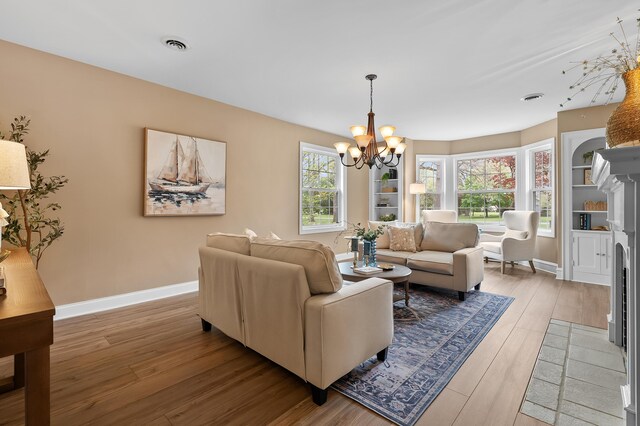 46132 86th Ave, Decatur, MI 49045 - living area with a chandelier, light wood finished floors, baseboards, and a fireplace with flush hearth