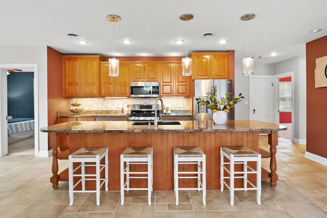 46132 86th Ave, Decatur, MI 49045 - kitchen featuring stainless steel appliances, a sink, tasteful backsplash, a kitchen island with sink, and baseboards
