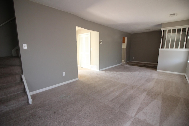 unfurnished room featuring light carpet, stairway, and baseboards