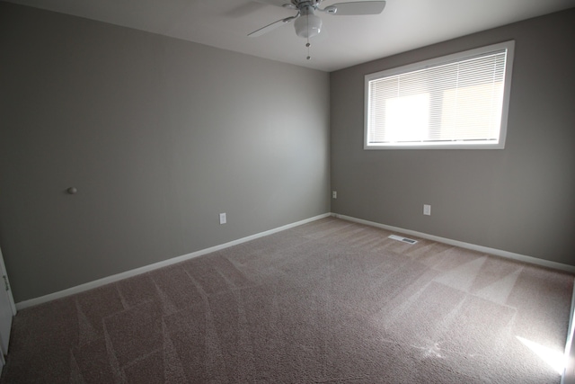 carpeted spare room featuring ceiling fan and baseboards