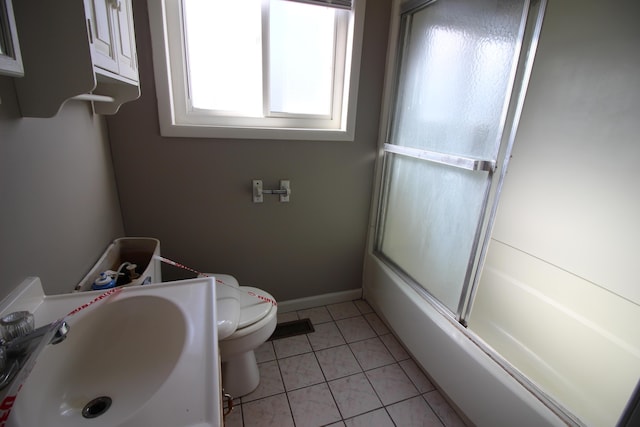 full bath with a sink, toilet, tile patterned flooring, baseboards, and bath / shower combo with glass door