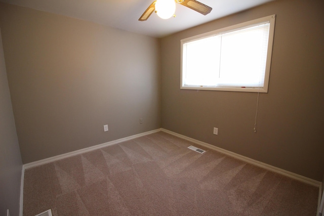 empty room featuring light colored carpet, a ceiling fan, and baseboards